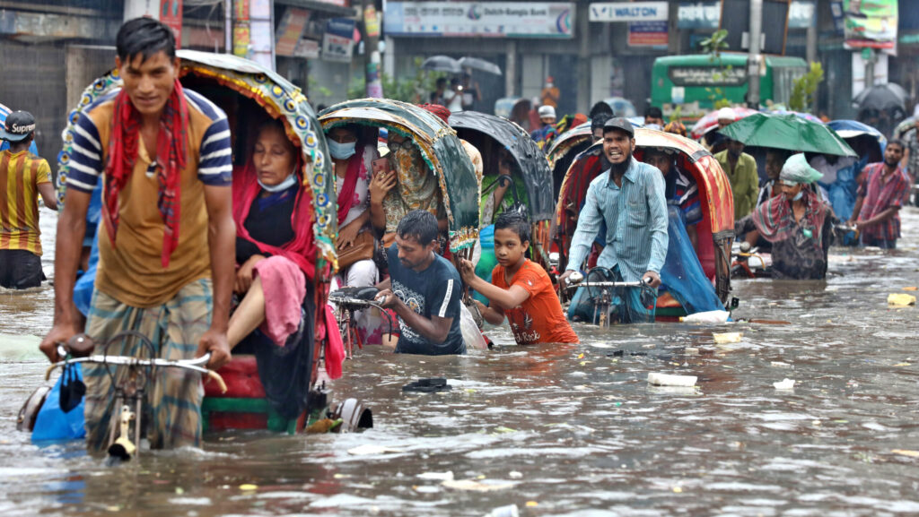 People standing in floodwater, illustrating the impact of recent natural hazards and climate risks such as floods and hurricanes, highlighting the dangers posed by natural disasters and extreme weather events.